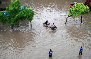 An aerial view of inundated road where vehicles struggling to pass through a rain-flooded street during a heavy monsoon downpour in the city.