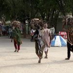 Villager women carry bundles of tree branches on their heads for domestic use as they head toward their destination