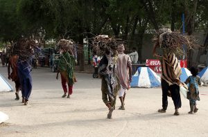 Villager women carry bundles of tree branches on their heads for domestic use as they head toward their destination