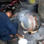 A worker puts the finishing touches on iron pots (digins) used for large banquets, over a roaring fire at an iron factory near Mochi Gate