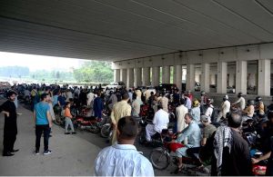 Girls riding a scooty move along the Expressway during rainfall in the Federal Capital.