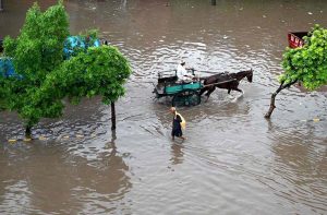 An aerial view of inundated road where vehicles struggling to pass through a rain-flooded street during a heavy monsoon downpour in the city.