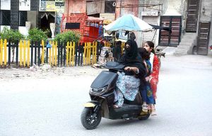 A woman rides a scooty with her children, a common sight on Pakistani roads these days as more women opt for this convenient mode of travel.
