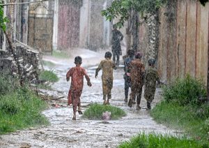 Boys enjoy play in the street during heavy Monsoon rain in the city.