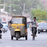 A youngster holding a rickshaw while cycling on busy Police Line Road, risking his life and violating traffic rules
