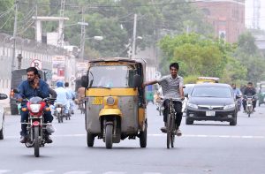 A youngster holding a rickshaw while cycling on busy Police Line Road, risking his life and violating traffic rules