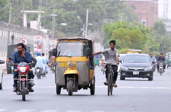 A youngster holding a rickshaw while cycling on busy Police Line Road, risking his life and violating traffic rules