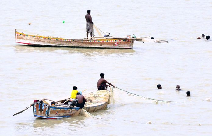 Fishermen busy in catching fish with fishing net on the boat at Indus River at Hussainabad