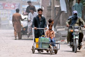 A youngster holding a rickshaw while cycling on busy Police Line Road, risking his life and violating traffic rules