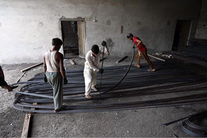 Labourers busy in bending and arranging iron rods at a steel workshop near I-9 area in the Federal Capital