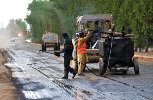 Labourers spray liquid tar on the surface of Bypass Road using heavy machinery, as part of ongoing construction work aimed at improving travel and infrastructure in the city.