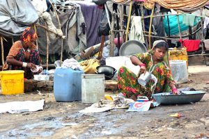 Gypsy women busy in washing the cloth outside their temporary hut near Railway Station area
