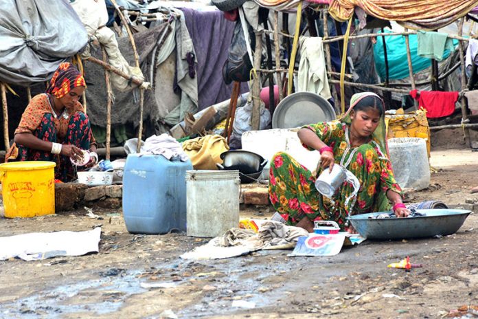Gypsy women busy in washing the cloth outside their temporary hut near Railway Station area