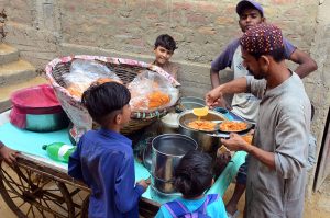 A vendor selling traditional food items daal papri to the customers at Kumhar pura.