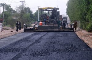 Labourers spray liquid tar on the surface of Bypass Road using heavy machinery, as part of ongoing construction work aimed at improving travel and infrastructure in the city.