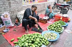 A vendor cuts pickled mangoes at his roadside stall, preparing them for eager customers