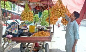 A vendor arranging and displaying fresh dates on his handcart to attract the customers.