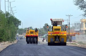Labourers spray liquid tar on the surface of Bypass Road using heavy machinery, as part of ongoing construction work aimed at improving travel and infrastructure in the city.