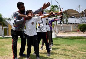 A trainer instructs archery players on how to aim and hit the target during a training session at Qayum Sports Complex.