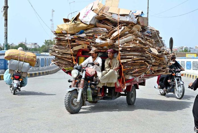 An overloaded loader rickshaw navigates the Railway Overbridge Road, reflecting unsafe commuting practices on busy routes in the city