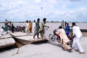 People load motorcycles and other equipment onto boats to cross the Sutlej River in the Nawahi area. AP