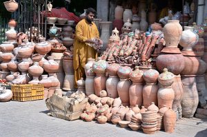 A vendor arranging and displaying clay made pots at his roadside setup near Zulfiqar Bagh