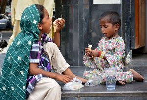 Gypsy girls sit on the shop floor along District Council Road, eating their meal together.