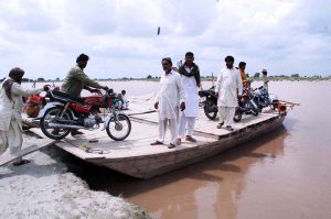 People load motorcycles and other equipment onto boats to cross the Sutlej River in the Nawahi area. AP