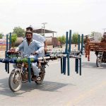 Two motorcyclists transport bed frames and traditional charpais on their way to their destination at Naag Shah Chowk