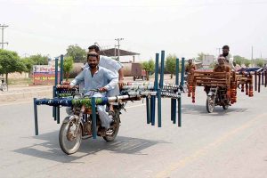 Two motorcyclists transport bed frames and traditional charpais on their way to their destination at Naag Shah Chowk