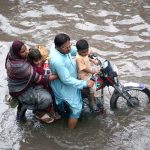 A family on a motorcycle struggles to make its way through rainwater flooding Jhumra Road near Nishatabad Bridge after a heavy downpour, causing traffic disruption and public inconvenience