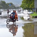 Vehicles navigate through stagnant rainwater following heavy rainfall in the Federal Capital