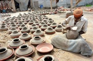 A worker busy in preparing the clay-made pots at his workplace.