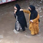 Women wade through rainwater on Jhumra Road near Nishatabad Bridge causing public inconvenience after a monsoon downpour