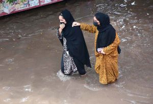 Women wade through rainwater on Jhumra Road near Nishatabad Bridge causing public inconvenience after a monsoon downpour
