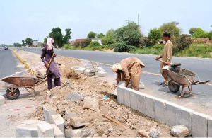 Labourers are busy constructing a road divider with cement blocks to ensure smooth traffic flow and safety near highway in the outskirts of the city.