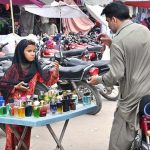 A young girl sells perfumes of various scents and colors on Empress Road to support her family's livelihood