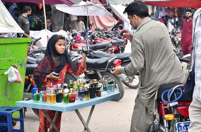 A young girl sells perfumes of various scents and colors on Empress Road to support her family's livelihood