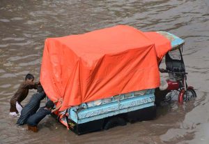 A family on a motorcycle struggles to make its way through rainwater flooding Jhumra Road near Nishatabad Bridge after a heavy downpour, causing traffic disruption and public inconvenience
