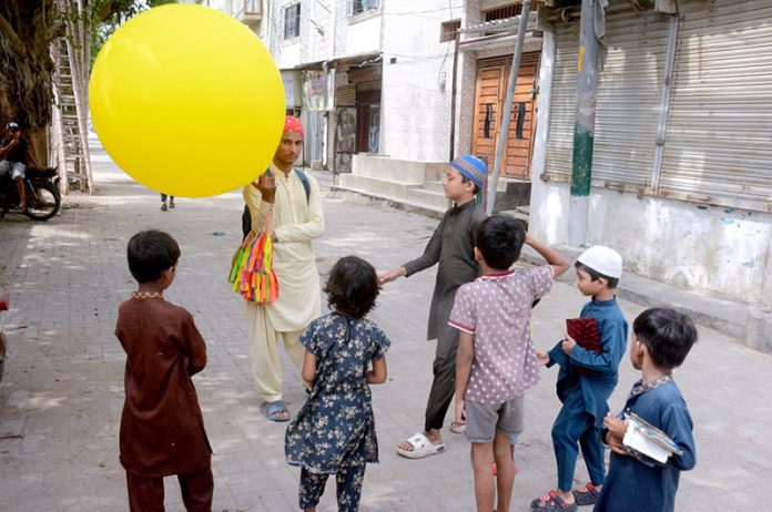 A street vendor in the Korangi area attracts children by selling balloons