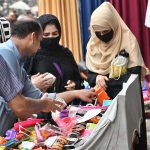 Women shop for children's toys from a handcart vendor, adding joy to little ones' live