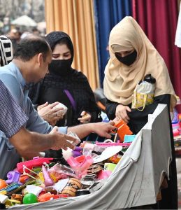 Women shop for children's toys from a handcart vendor, adding joy to little ones' live