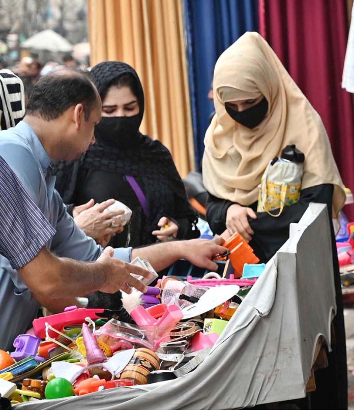 Women shop for children's toys from a handcart vendor, adding joy to little ones' live