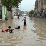 Children enjoy bathe in rainwater accumulated on Makki Shah Road, which was submerged following heavy rainfall