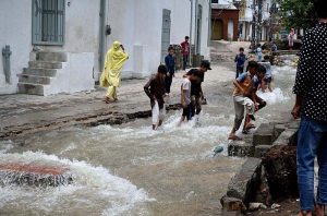 Children enjoy bathing, jumping, and splashing in flooded streets after a torrential downpour in Saidpur Village of the Federal Capital