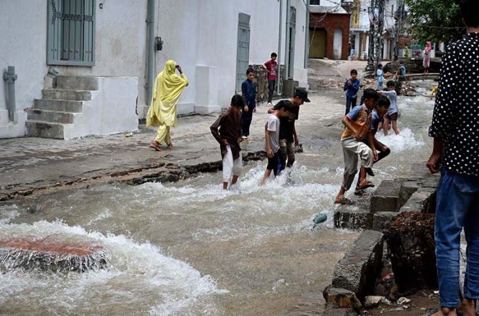 Children enjoy bathing, jumping, and splashing in flooded streets after a torrential downpour in Saidpur Village of the Federal Capital