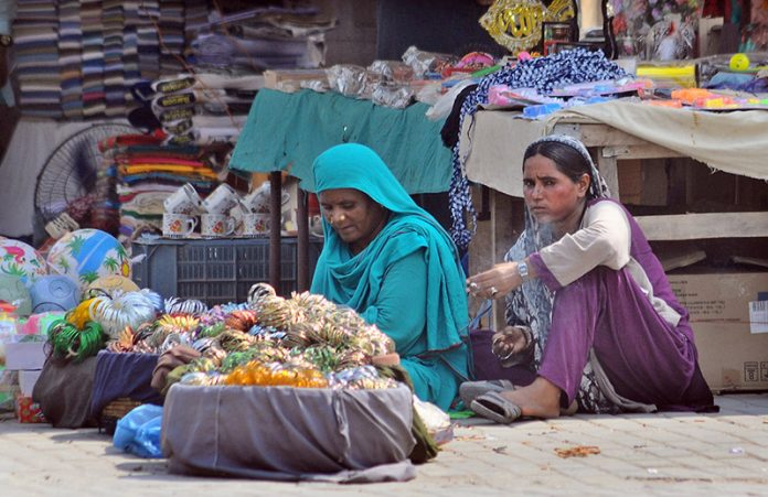 Women vendors waiting for customers to sell colorful bangles at their roadside stall in a local market