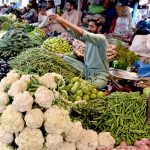 A vendor displays vegetables to attract customers at a local vegetable market