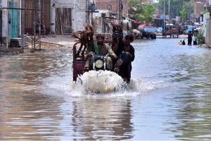 Children enjoy bathe in rainwater accumulated on Makki Shah Road, which was submerged following heavy rainfall