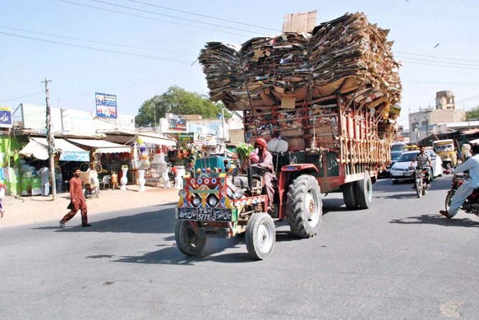 A tractor trolley overloaded with recycle cardboard disrupts traffic flow, highlighting the need for action by traffic authorities